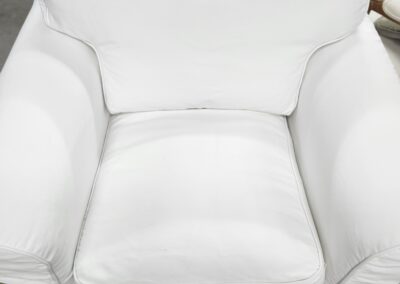 A clean white armchair with plush cushions.