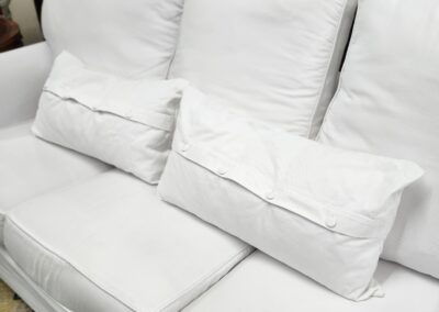 A cozy white couch with cushions in a living room.