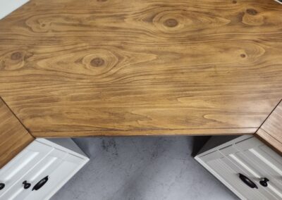 Wooden desk top with a natural grain pattern and two gray drawers underneath.