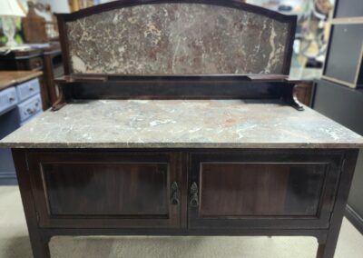 Antique wooden bench with worn finish and storage cabinet beneath.
