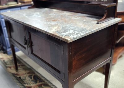 Antique wooden sideboard with marble top and ornate detailing.