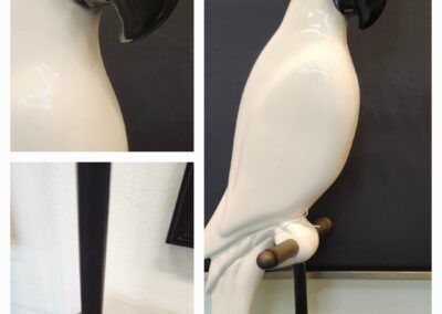 Decorative white cockatoo sculpture with black and yellow accents on a stand.