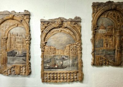 Three ornate wooden panels with carved cityscape and bridge designs.