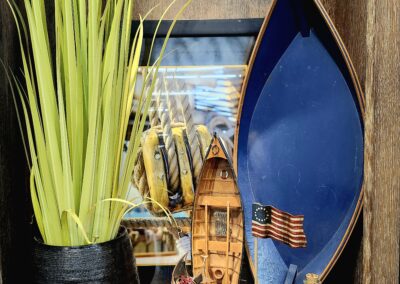 Decorative blue boat with green plant and cultural artifacts on a textured wall.