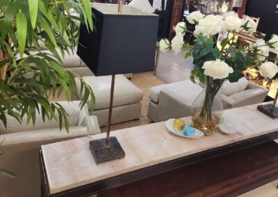 Square black table lamp on a marble surface beside a vase of white flowers.