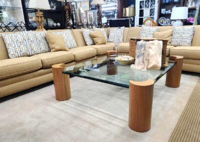 Modern glass coffee table with wooden cylindrical legs in a cozy living room.