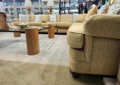 Cozy beige sectional sofa with cylindrical wooden side tables in a spacious living room.