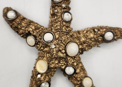 Starfish-shaped wall decor adorned with shells and beads.