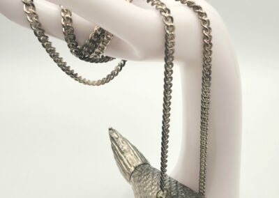 A silver pendant shaped like a pointed object on a chain necklace.
