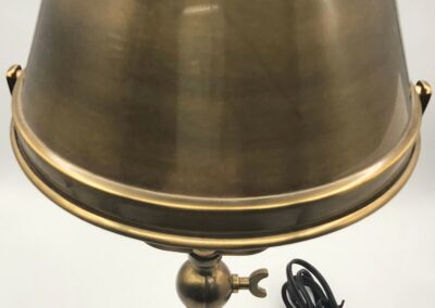 Antique brass table lamp with a conical shade and a black cord.