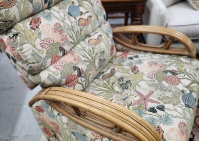 A floral cushioned chair with wooden armrests.