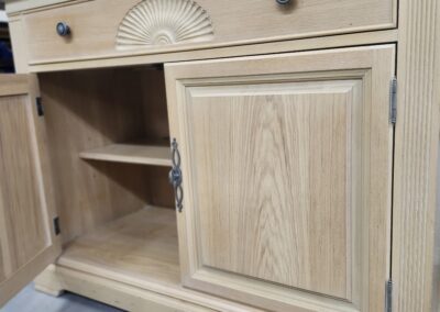 Light wooden cabinet with open and closed doors showing shelves inside.