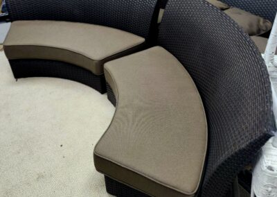 Curved sectional sofa with dark frame and beige cushions.