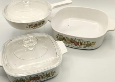Vintage white casserole dishes with floral patterns and glass lids.