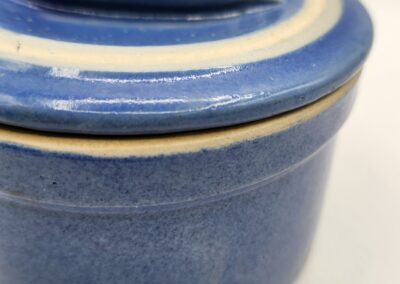 Close-up of a blue ceramic container with a lid and a yellow rim.