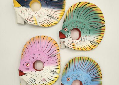 Four colorful, round fish-shaped ceramic plates with spiral designs.