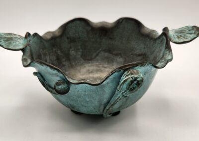 A decorative green ceramic bowl with a scalloped rim and floral accents.