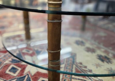 A vintage wooden telescope on a glass table with a patterned rug underneath.