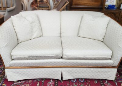 Elegant white loveseat with two matching cushions on a patterned rug.