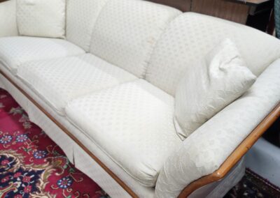 Elegant white upholstered sofa with wooden frame on a patterned rug.
