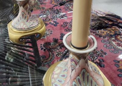 Elegant ceramic candle holders with cream candles on a patterned tablecloth.