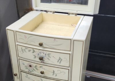 Tall cream-colored jewelry cabinet with open top storage and multiple drawers.