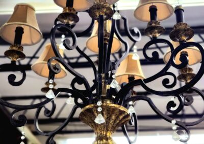 Elegant black and gold chandelier with cream lampshades in a bright room.