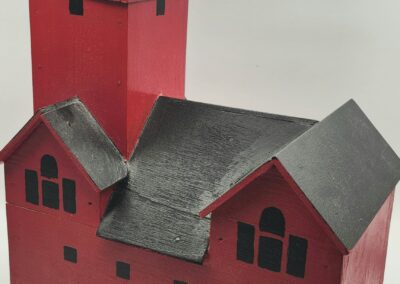 A red model house with a tall chimney and black roof details.