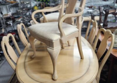 Wooden chair placed upside-down on a round wooden table surrounded by similar chairs.