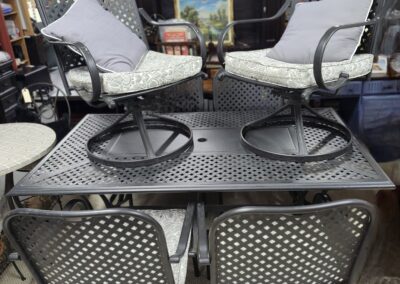 Outdoor patio seating with two cushioned swivel chairs and a metal table.