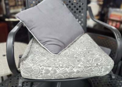 A cozy chair with a cushion and a gray pillow in a warm indoor setting.