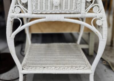 Vintage white wicker side table with intricate design and lower shelf.
