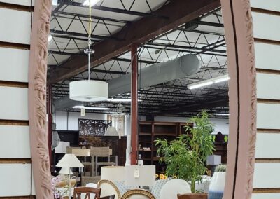 Oval mirror reflecting a furniture showroom with various chairs and decor.