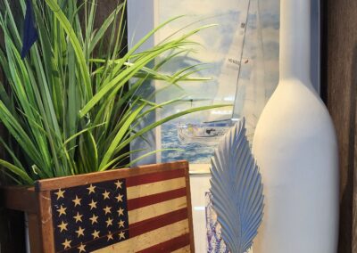 A decorative American flag box, tall white vase, and green plant on a wooden surface.