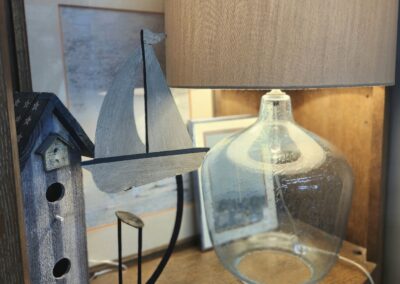 A glass cloche on a wooden surface near a birdhouse and lamp.