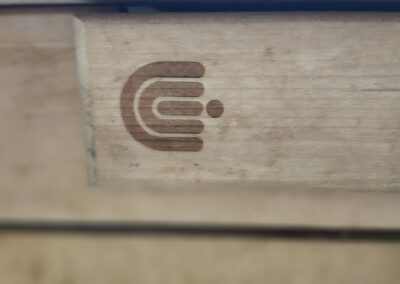 A wooden surface with a branded logo featuring stylized lines and dots.