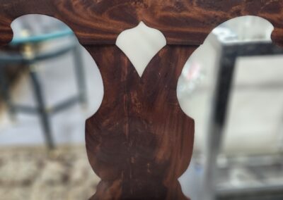 Close-up of a carved wooden chair back with a white cushion.