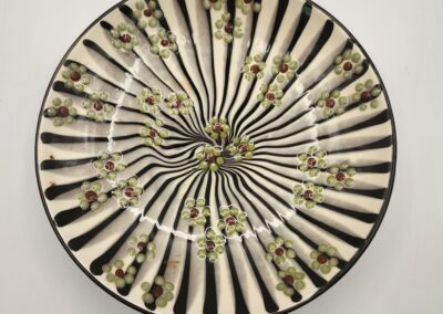 Decorative circular plate with a floral and striped pattern.