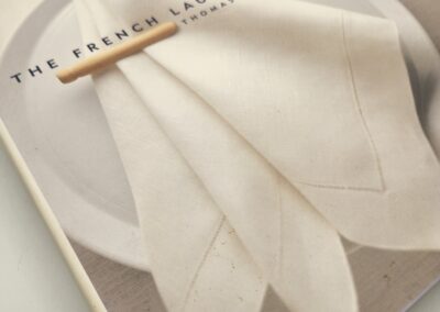 A pencil resting on a book titled 'THE FASHION BOOK' with a subtle fabric design.
