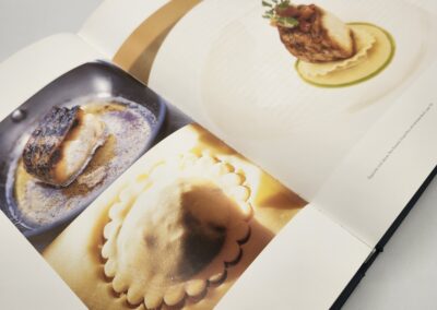 A cookbook showing ravioli and a plated dish with sauce and garnish.