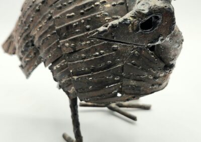 A rustic bird sculpture made of textured metal with detailed features.