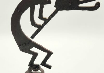 A metal sculpture of a figure playing a flute.