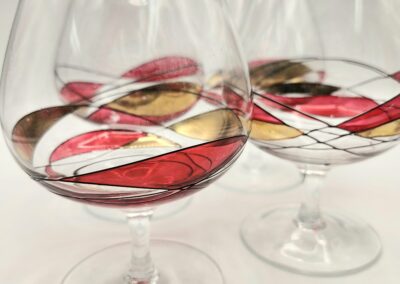 Two glasses with clear liquid and red flower petals inside on a white surface.