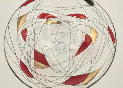 Abstract circular artwork with red, black, and gold shapes intertwined by black lines.