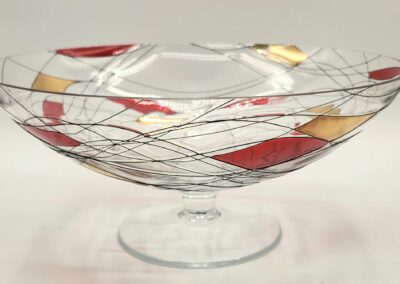 Decorative glass bowl with colorful abstract patterns on a pedestal.