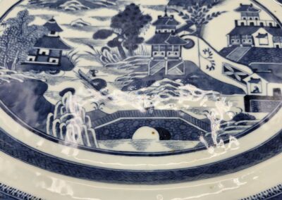 Blue and white ceramic plate with a scenic village and bridge design.