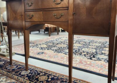 Antique wooden sideboard with brass handles on a Persian rug.