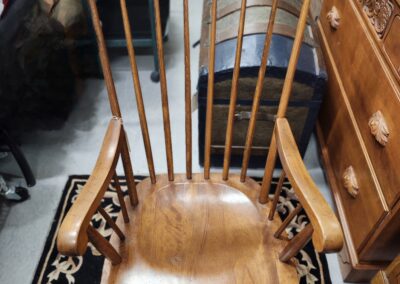 Wooden rocking chair with a curved seat and vertical slats backrest.