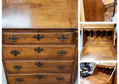 Antique wooden chest of drawers with ornate brass handles and a pull-out writing surface.