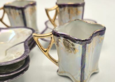 Elegant vintage glass cups with gold handles and iridescent finish.